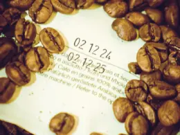 Granos de café encima de un envase donde se puede ver la fecha de tueste